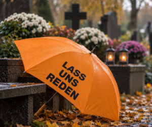 Orangefarbener Schirm der Aktion „Lass uns reden“ auf einem Friedhof (KI-generiertes Bild)