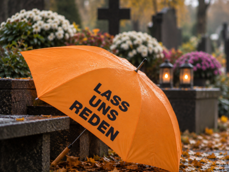 Orangefarbener Schirm der Aktion „Lass uns reden“ auf einem Friedhof (KI-generiertes Bild)